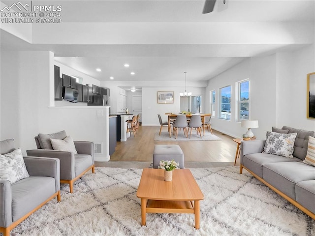 living room with ceiling fan with notable chandelier and light hardwood / wood-style floors