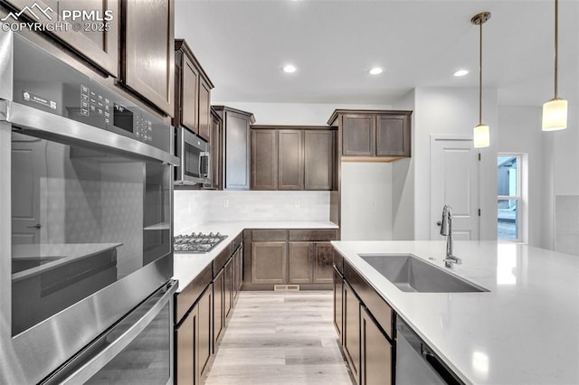 5265 Gansevoort Dr, Colorado Springs, CO 80927 - kitchen with appliances with stainless steel finishes, tasteful backsplash, light wood-style floors, dark brown cabinets, and pendant lighting