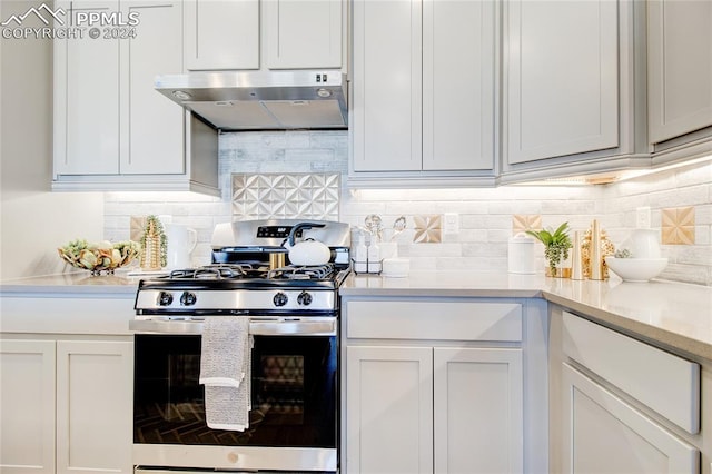 kitchen featuring white cabinets, exhaust hood, backsplash, and stainless steel gas range