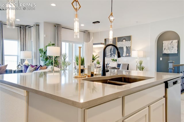 kitchen with hanging light fixtures, sink, white dishwasher, and a healthy amount of sunlight