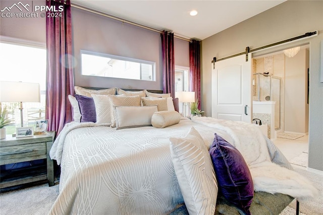 bedroom featuring connected bathroom, a barn door, and carpet