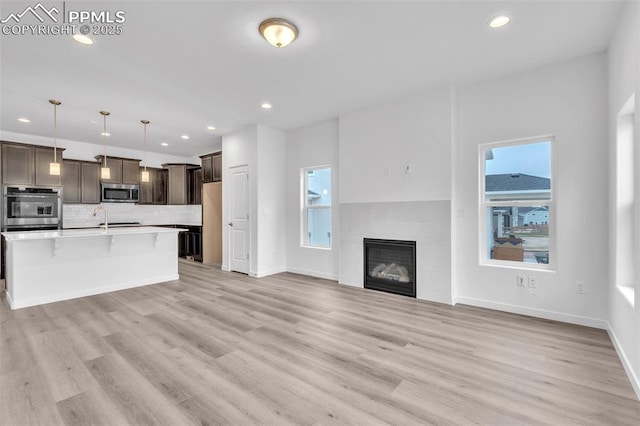 5265 Gansevoort Dr, Colorado Springs, CO 80927 - kitchen featuring stainless steel appliances, open floor plan, dark brown cabinetry, light wood finished floors, and recessed lighting