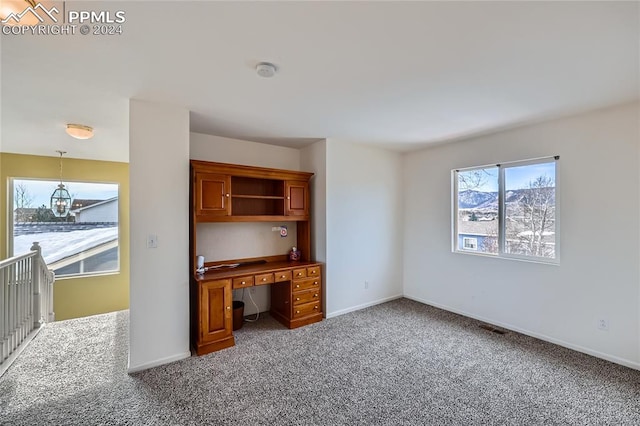 unfurnished office featuring carpet floors and an inviting chandelier