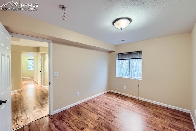 empty room with wood-type flooring and a textured ceiling