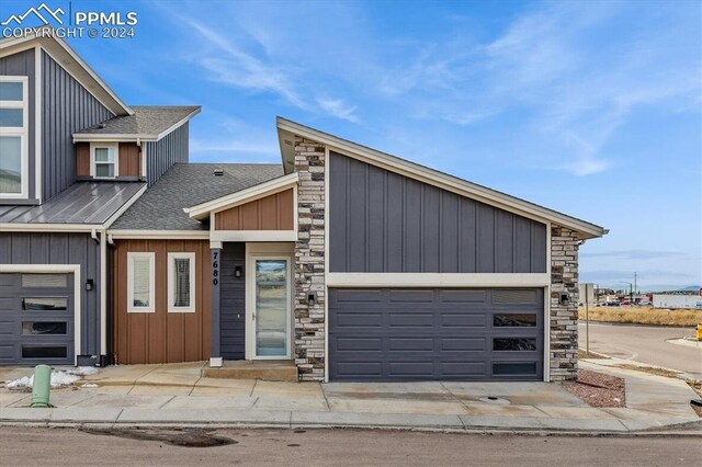7680 Almond Wood Loop, Colorado Springs, CO 80908 - view of front of house with stone siding, a shingled roof, an attached garage, and concrete driveway