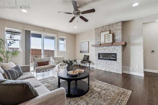 living room with a stone fireplace, ceiling fan, and dark hardwood / wood-style floors