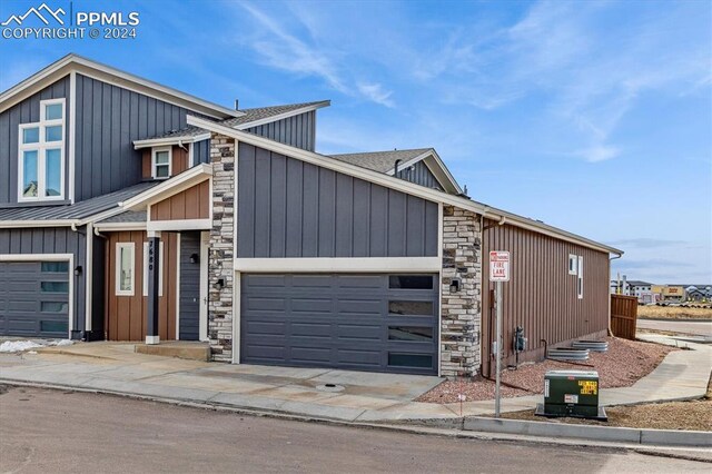 7680 Almond Wood Loop, Colorado Springs, CO 80908 - view of front of house with stone siding, board and batten siding, a garage, and concrete driveway
