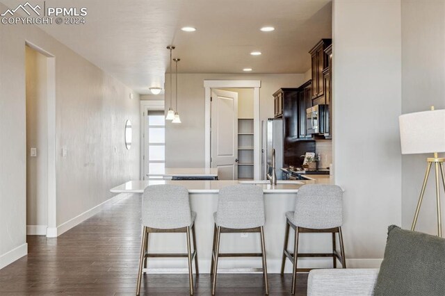 7680 Almond Wood Loop, Colorado Springs, CO 80908 - kitchen with appliances with stainless steel finishes, dark wood finished floors, dark brown cabinetry, light countertops, and a peninsula