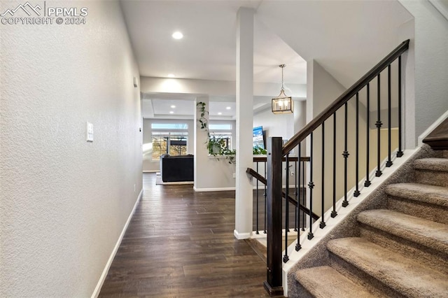 stairway with a chandelier and hardwood / wood-style flooring