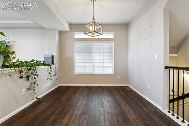 empty room featuring dark hardwood / wood-style flooring and a notable chandelier