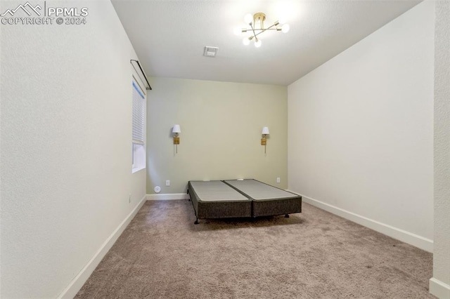 bedroom with light colored carpet and a chandelier