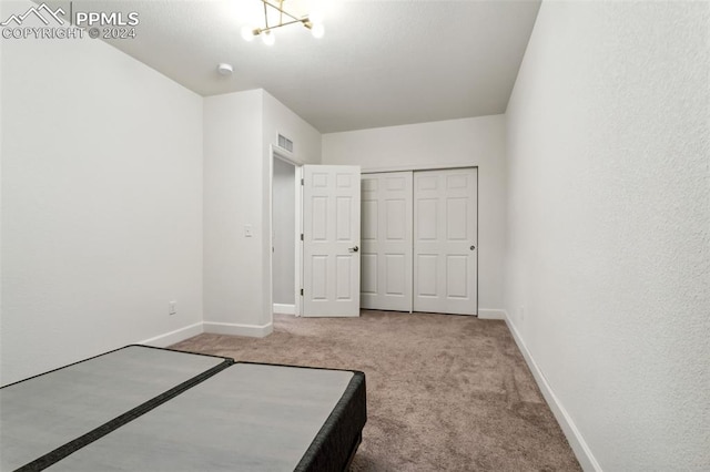 unfurnished bedroom featuring carpet, a notable chandelier, and a closet