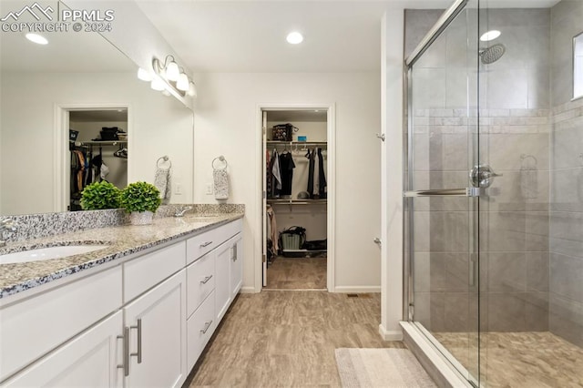 bathroom with hardwood / wood-style floors, vanity, and a shower with shower door