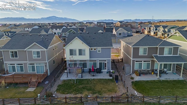 rear view of property with a lawn, a mountain view, and a patio