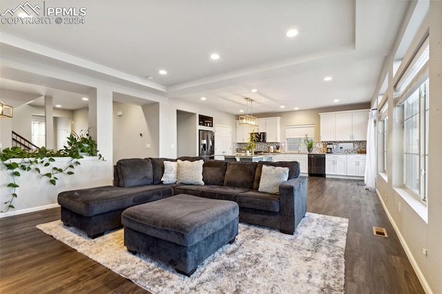 living room with dark wood-type flooring and a tray ceiling