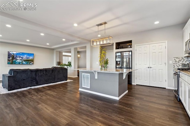 kitchen with white cabinetry, stainless steel appliances, a kitchen breakfast bar, light stone counters, and decorative light fixtures