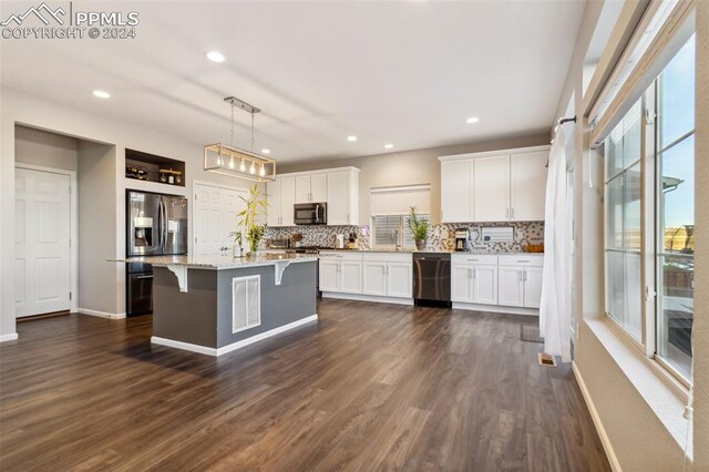 kitchen with stainless steel appliances, dark wood-type flooring, decorative light fixtures, white cabinets, and a kitchen island