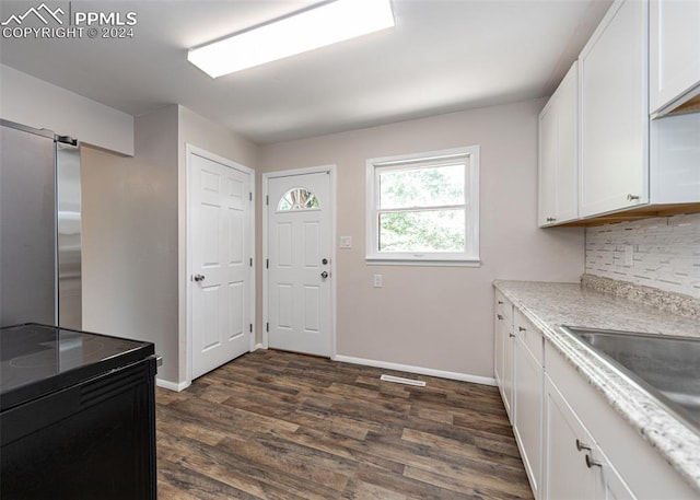 kitchen with backsplash, stainless steel fridge, white cabinetry, and dark hardwood / wood-style floors