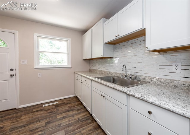 kitchen featuring decorative backsplash, light stone counters, sink, dark hardwood / wood-style floors, and white cabinetry