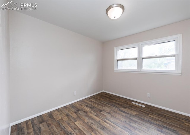 unfurnished room featuring dark wood-type flooring and a wealth of natural light