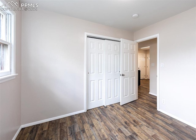 unfurnished bedroom with a closet and dark hardwood / wood-style floors