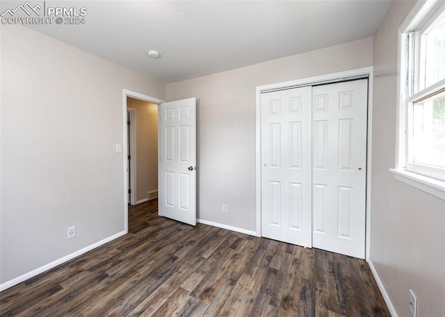 unfurnished bedroom with dark hardwood / wood-style floors and a closet