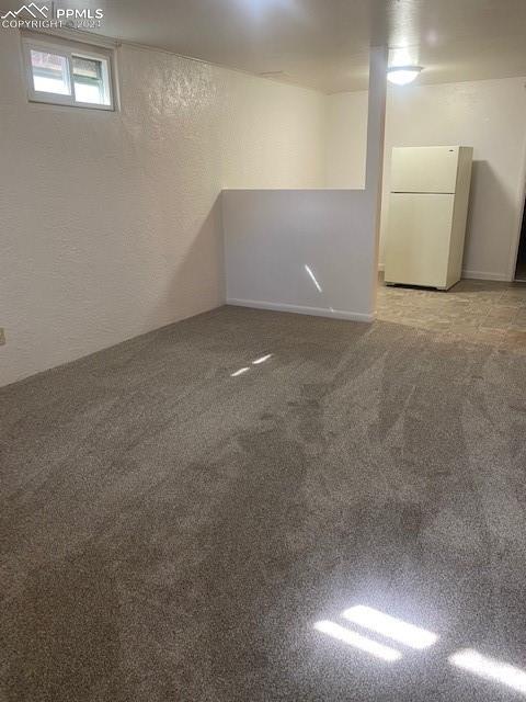 basement featuring light carpet and white fridge