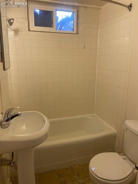 bathroom featuring tile patterned floors, tiled shower / bath, and toilet