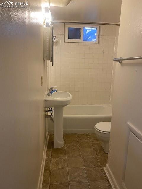 bathroom featuring tile patterned floors, toilet, and tiled shower / bath