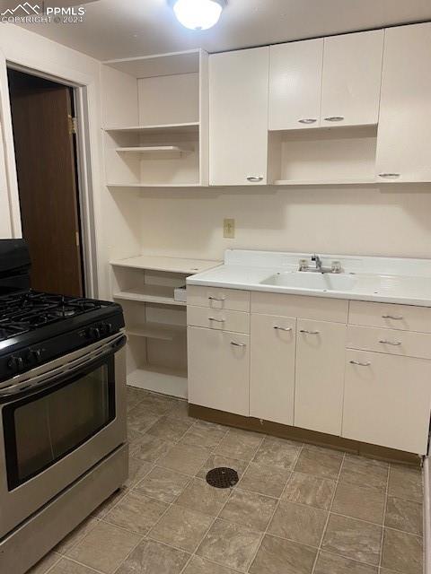 kitchen featuring white cabinets, stainless steel range with gas cooktop, and sink