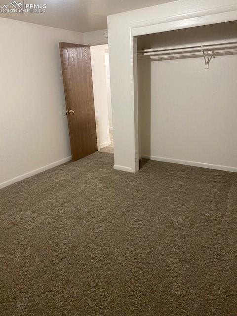 unfurnished bedroom with dark carpet and a closet