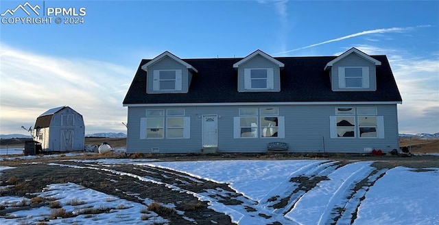 cape cod-style house featuring a storage unit