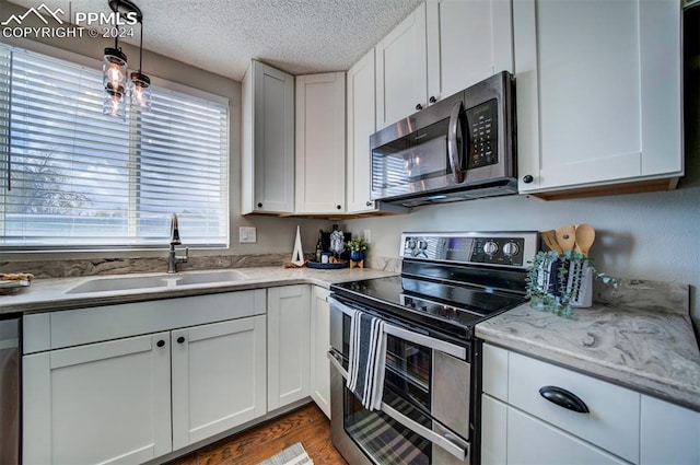 kitchen with sink, white cabinets, a textured ceiling, and appliances with stainless steel finishes