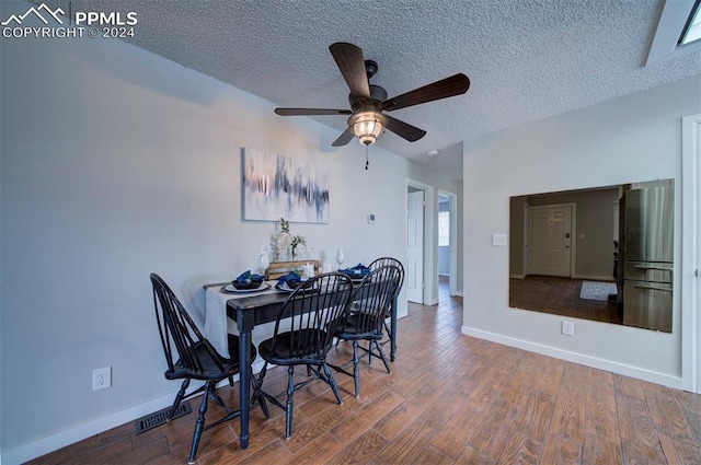 dining area with hardwood / wood-style floors, ceiling fan, and a textured ceiling