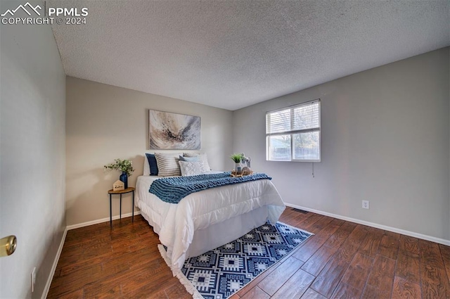 bedroom featuring dark hardwood / wood-style flooring and a textured ceiling