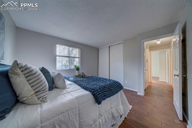 bedroom featuring hardwood / wood-style floors, a textured ceiling, and a closet