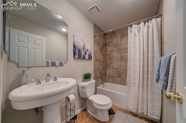 bathroom with tile patterned floors, shower / bath combination with curtain, toilet, and a textured ceiling