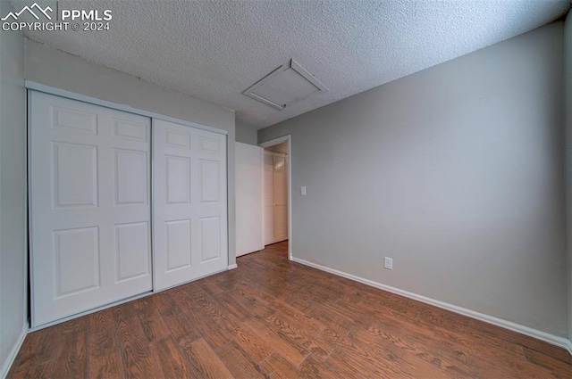 unfurnished bedroom featuring a textured ceiling and dark wood-type flooring