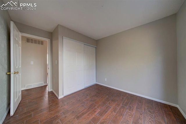 unfurnished bedroom featuring dark wood-type flooring and a closet