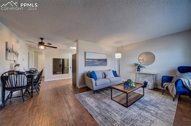 living room featuring ceiling fan, dark hardwood / wood-style flooring, and a textured ceiling