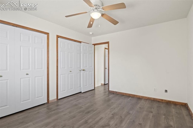 unfurnished bedroom featuring hardwood / wood-style floors, ceiling fan, and multiple closets