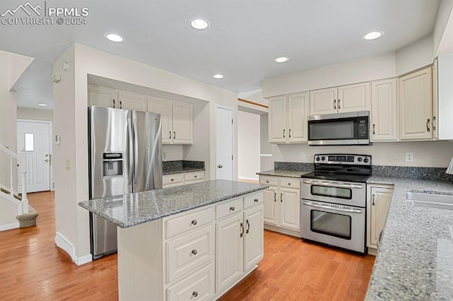 kitchen with a center island, light hardwood / wood-style floors, light stone countertops, and stainless steel appliances