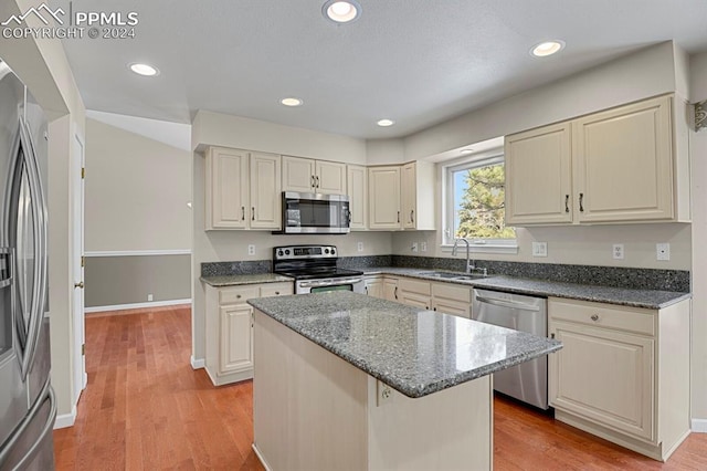 kitchen featuring dark stone counters, sink, light hardwood / wood-style flooring, a kitchen island, and stainless steel appliances