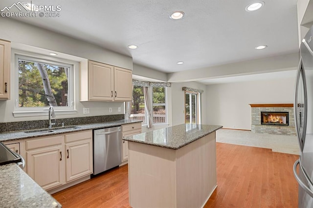 kitchen with light stone countertops, appliances with stainless steel finishes, light hardwood / wood-style floors, and a healthy amount of sunlight