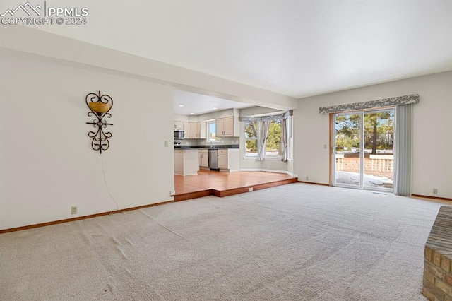 unfurnished living room featuring light colored carpet