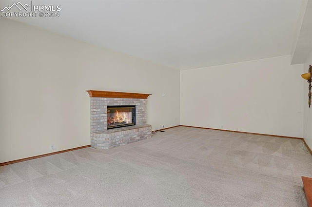 unfurnished living room with carpet flooring and a brick fireplace