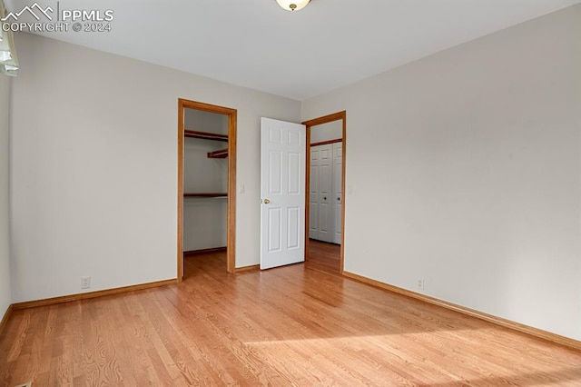 unfurnished bedroom with a walk in closet and light hardwood / wood-style floors