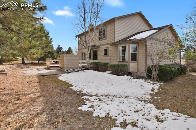 snow covered rear of property featuring a wooden deck