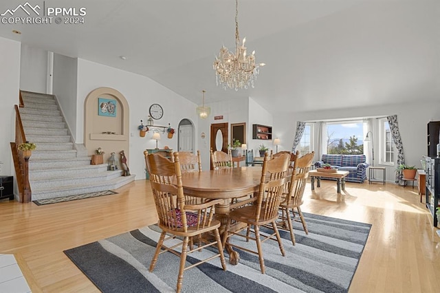 dining space featuring an inviting chandelier, light hardwood / wood-style flooring, and high vaulted ceiling