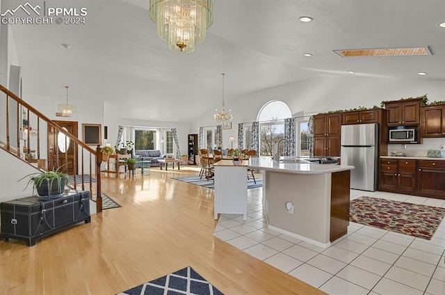 kitchen with plenty of natural light, stainless steel appliances, a center island with sink, and a notable chandelier